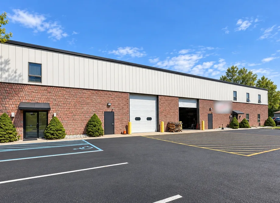 The brick and metal building at United Flex Medford: an entrance, two drive-in doors and the parking lot